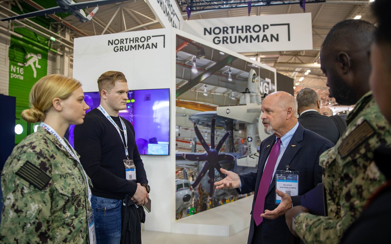 Des officiels et des militaires échangent devant le stand d'un exposant